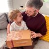 fils offrant une box cadeau fete des peres a son pere